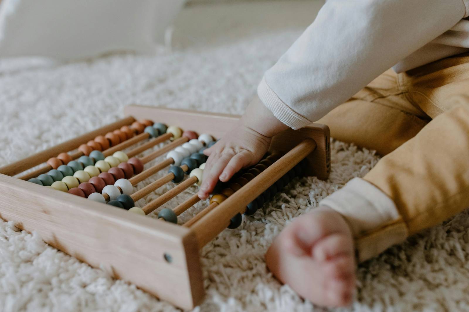 A child's hand moving beads on a wooden abacus